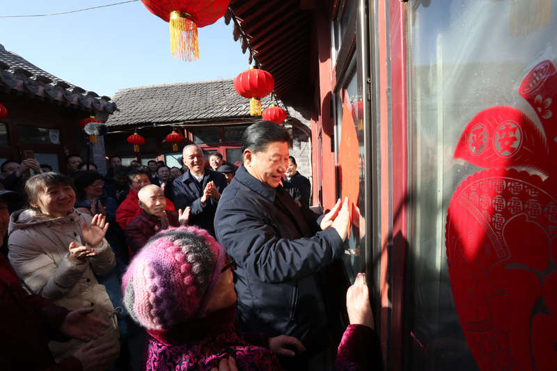 2019年2月1日上午，習近平在北京前門(mén)東區草廠(chǎng)四條胡同32號院，高興地拿起一幅“?！弊?，親自貼到門(mén)上，給這里的老街坊們拜年。新華社記者 鞠鵬 攝